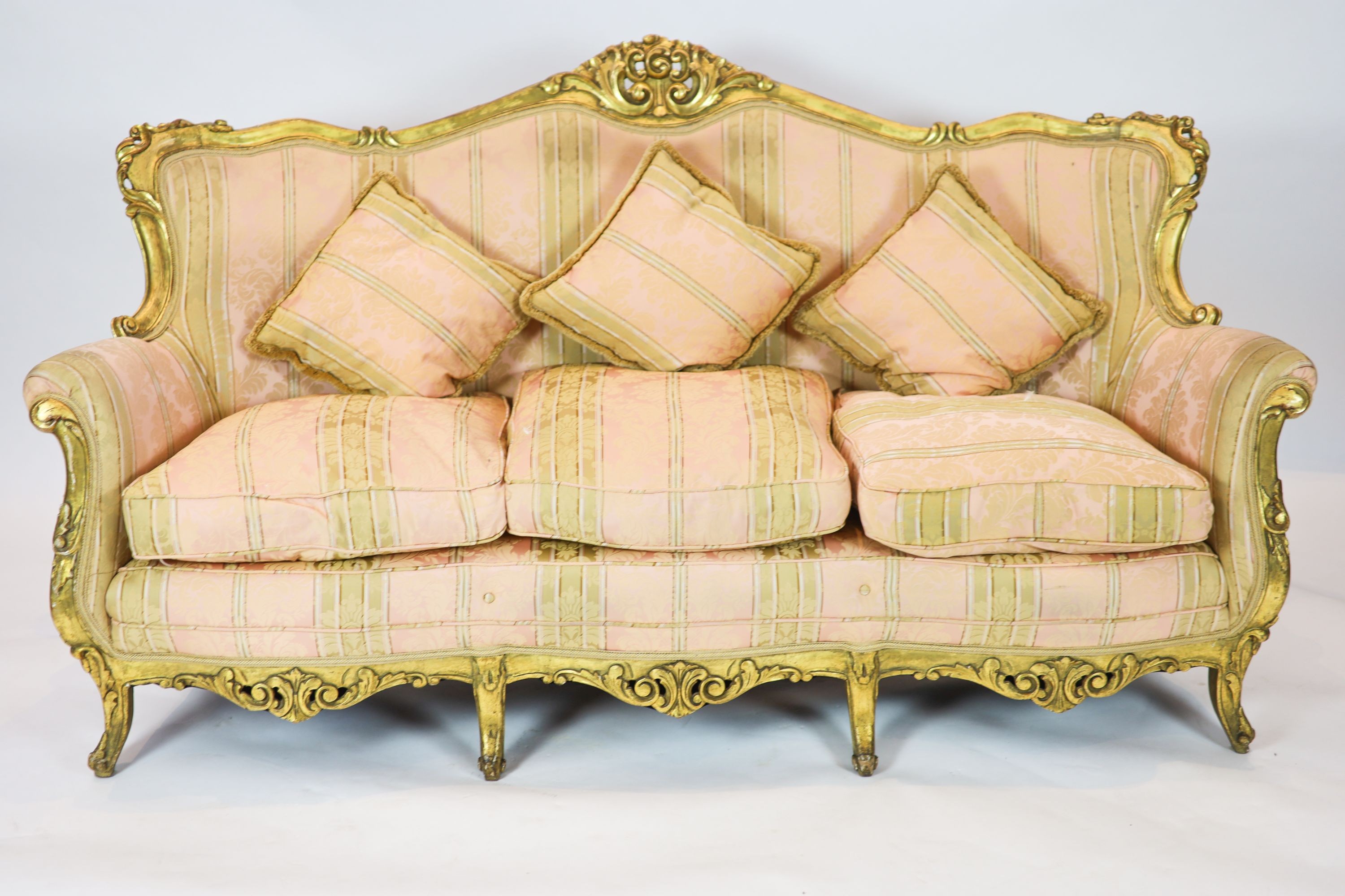 A Louis XV style carved gilt wood five piece suite, consisting of a three seater settee and four fauteuils, all with scroll carved backs and arms, on short cabriole legs